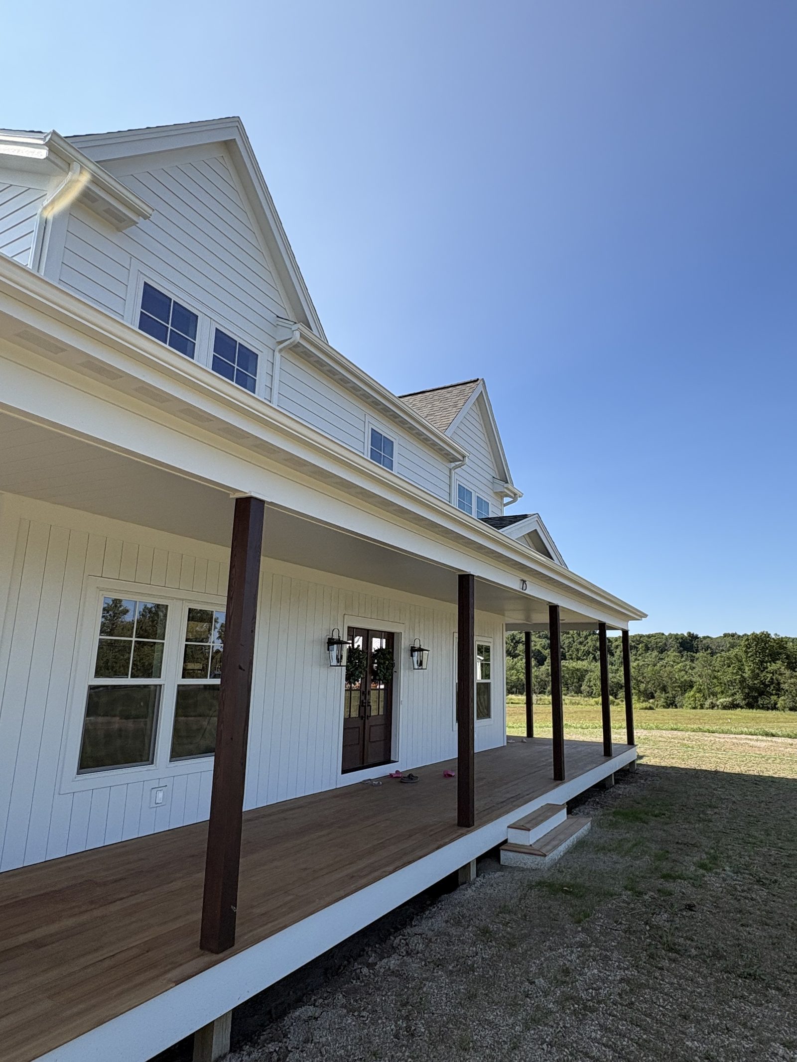 White farmhouse with a wraparound covered porch and new siding