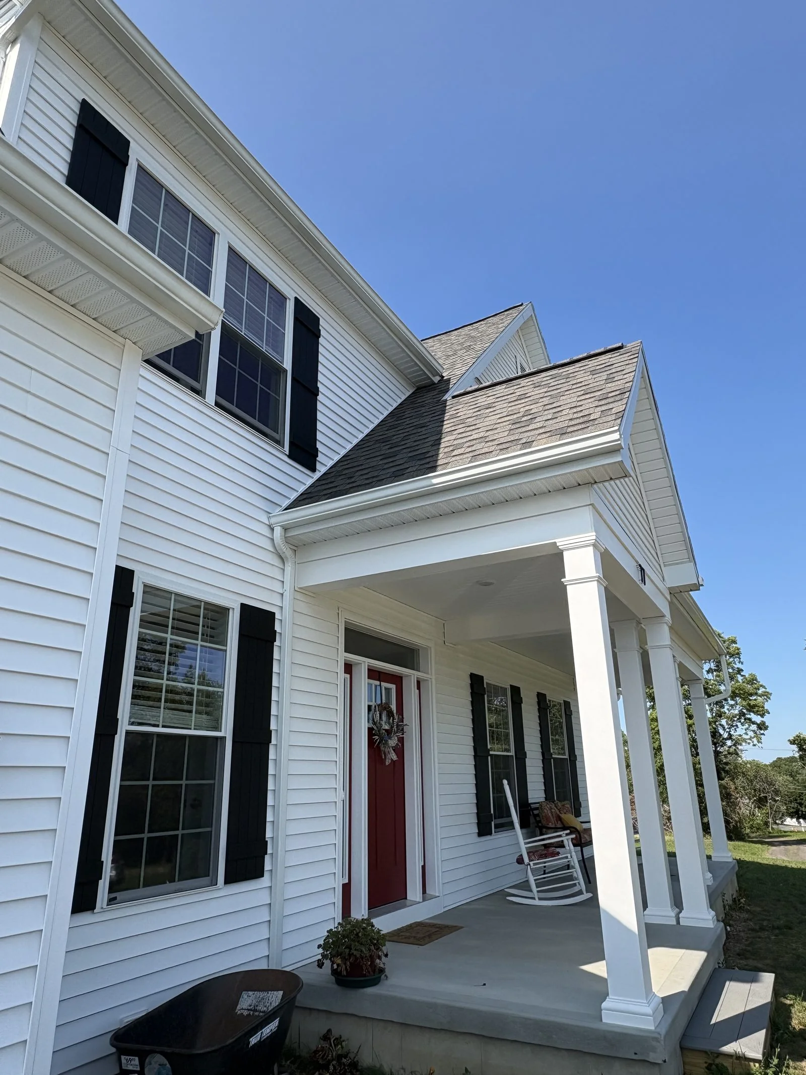 White-sided home with a covered entry and red door